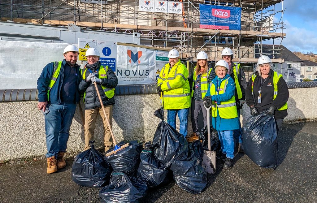 Adra and Novus staff outside Adra homes doing a clean up