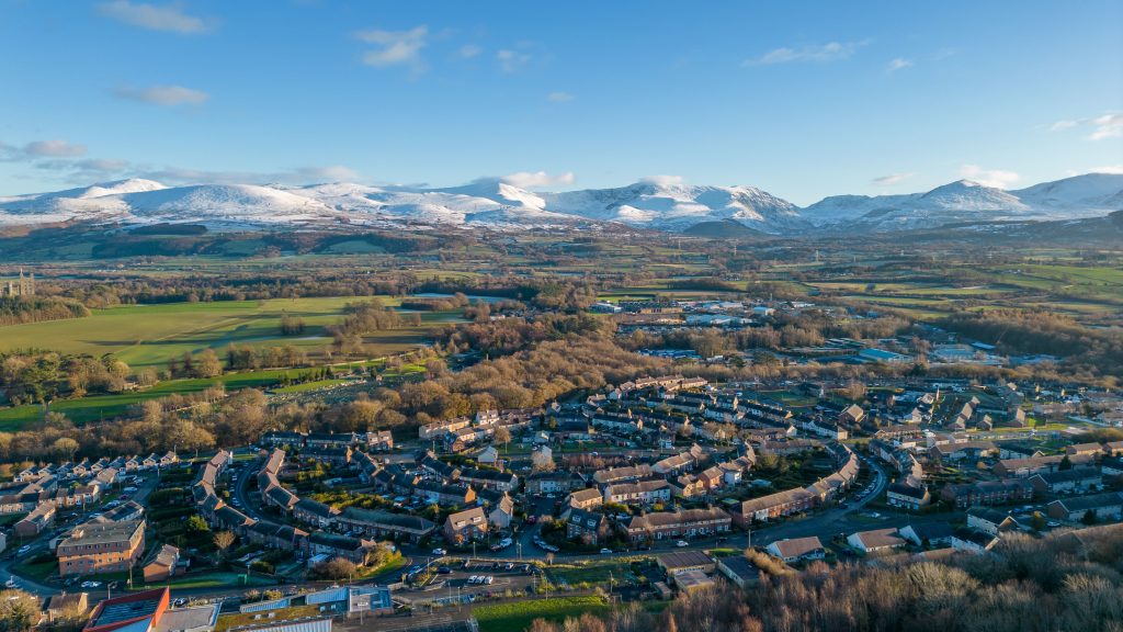 Llun o stad o dai gyda mynyddoedd yn y cefndir.