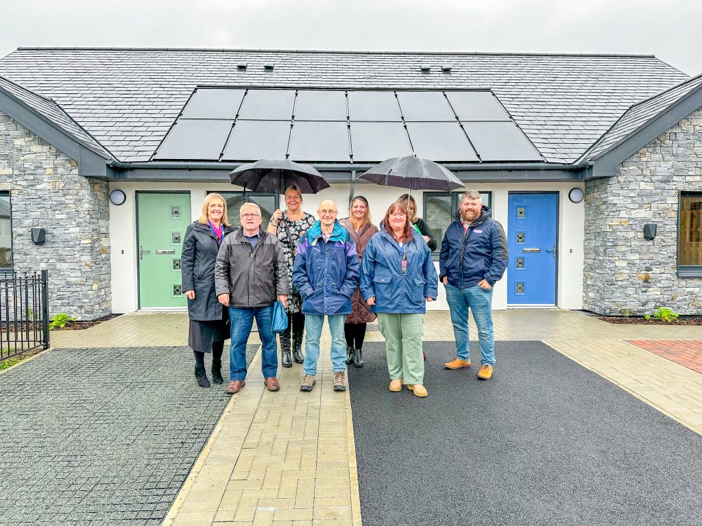 Photo of local councillors and Adra Officers in front of a bungalow at Cae Rhsoydd